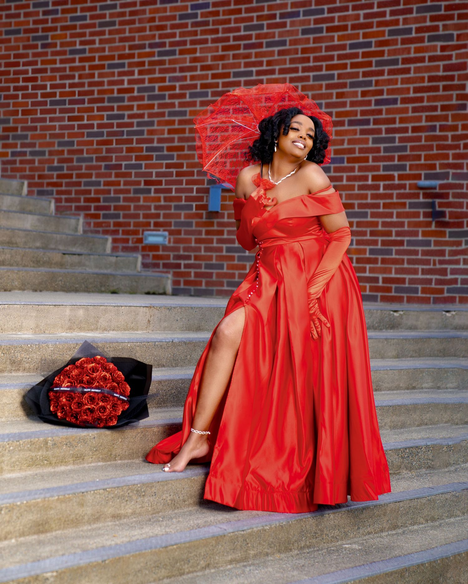 Stunning red gown with matching umbrella photographed on brick steps.