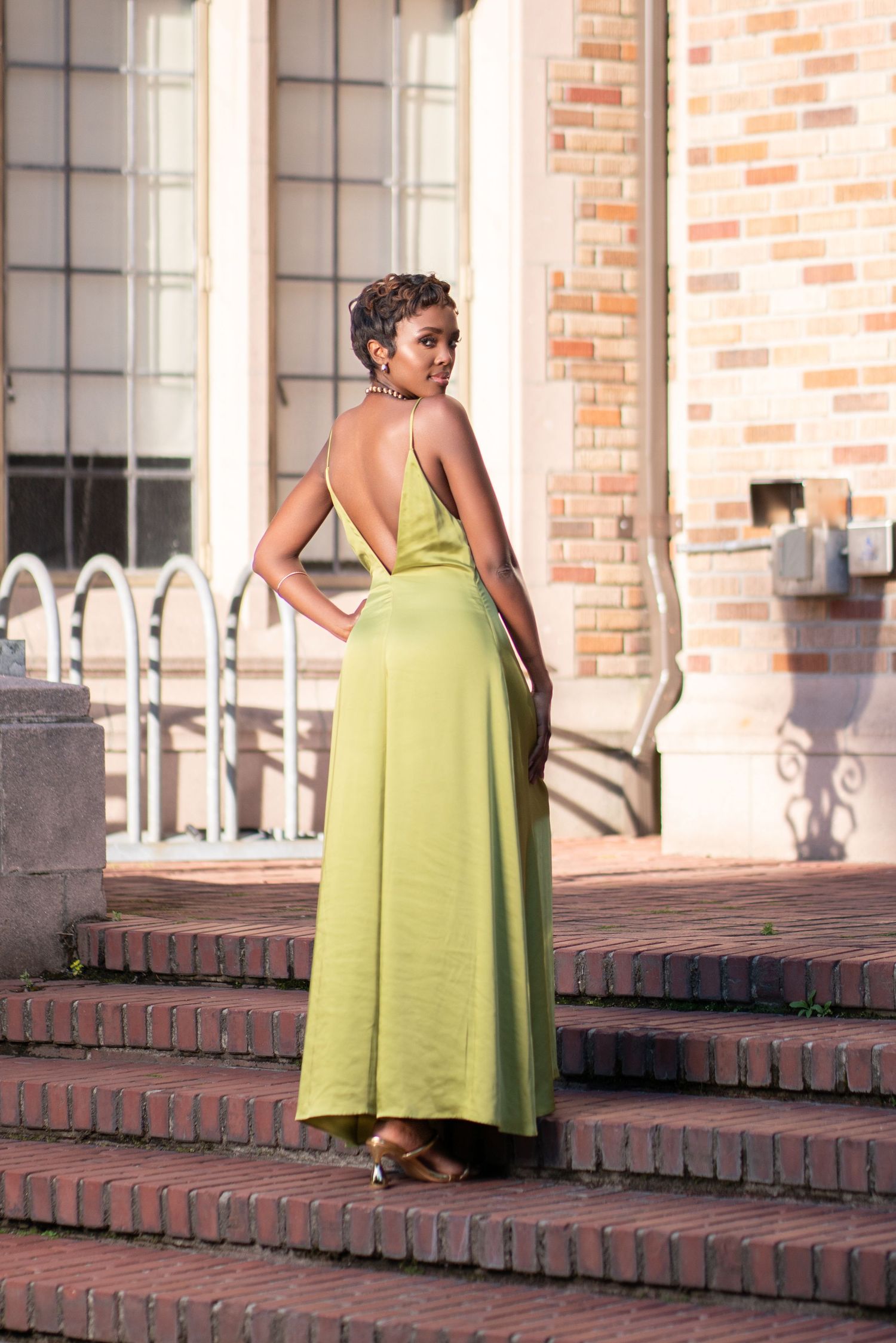 Fashion photo of lime green formal dress on brick steps with architectural backdrop.