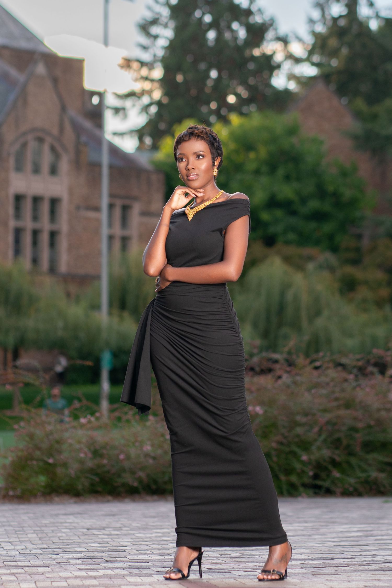 Elegant black evening gown portrait against gothic architecture backdrop.