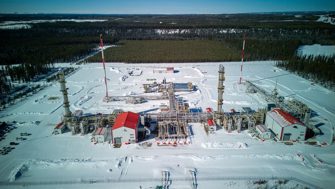 Aerial panoramic view of an industrial facility with multiple buildings and equipment in a snowy winter landscape.