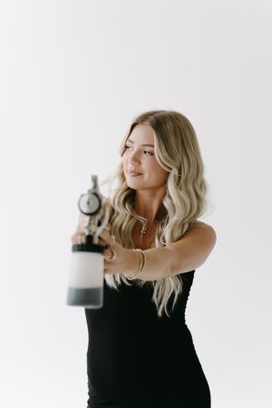 A figure in black holding a champagne bottle against a white background.