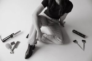 Black and white image of person with styling tools scattered on floor.