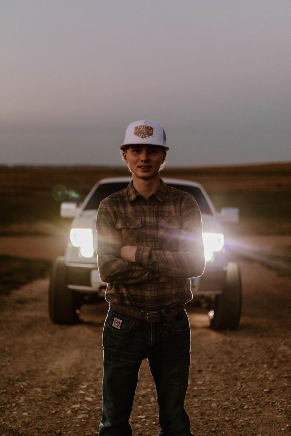 A nighttime portrait with truck headlights illuminating someone in front of a pickup truck.