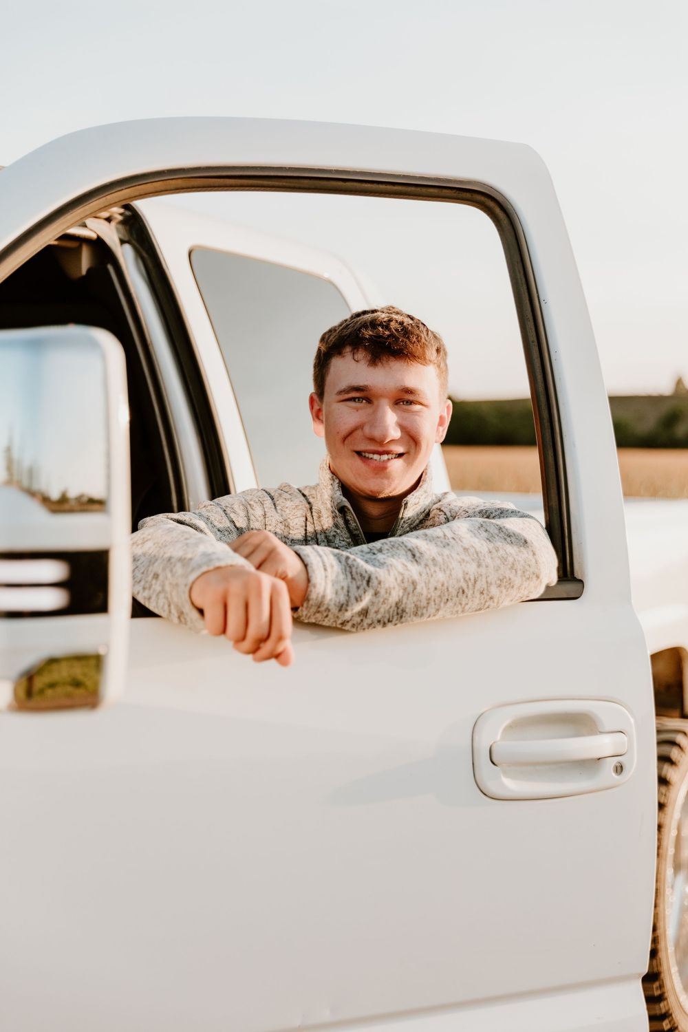 People smiling and looking out car windows during golden hour.