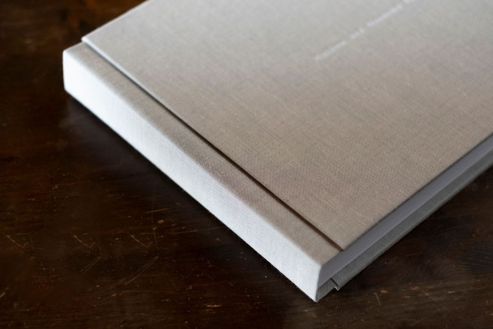 Close-up view of a hardcover book spine detail showing minimalist white binding against a dark wood surface.