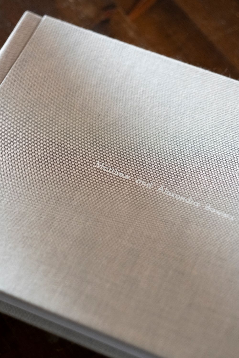 A series of wedding album pages with elegant text fading across textured linen paper in a soft beige color.