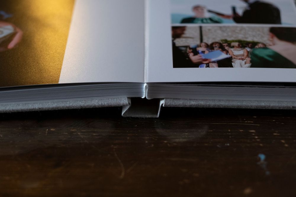 Close-up view of a photo album binding showing the spine and pages against a dark wooden surface.