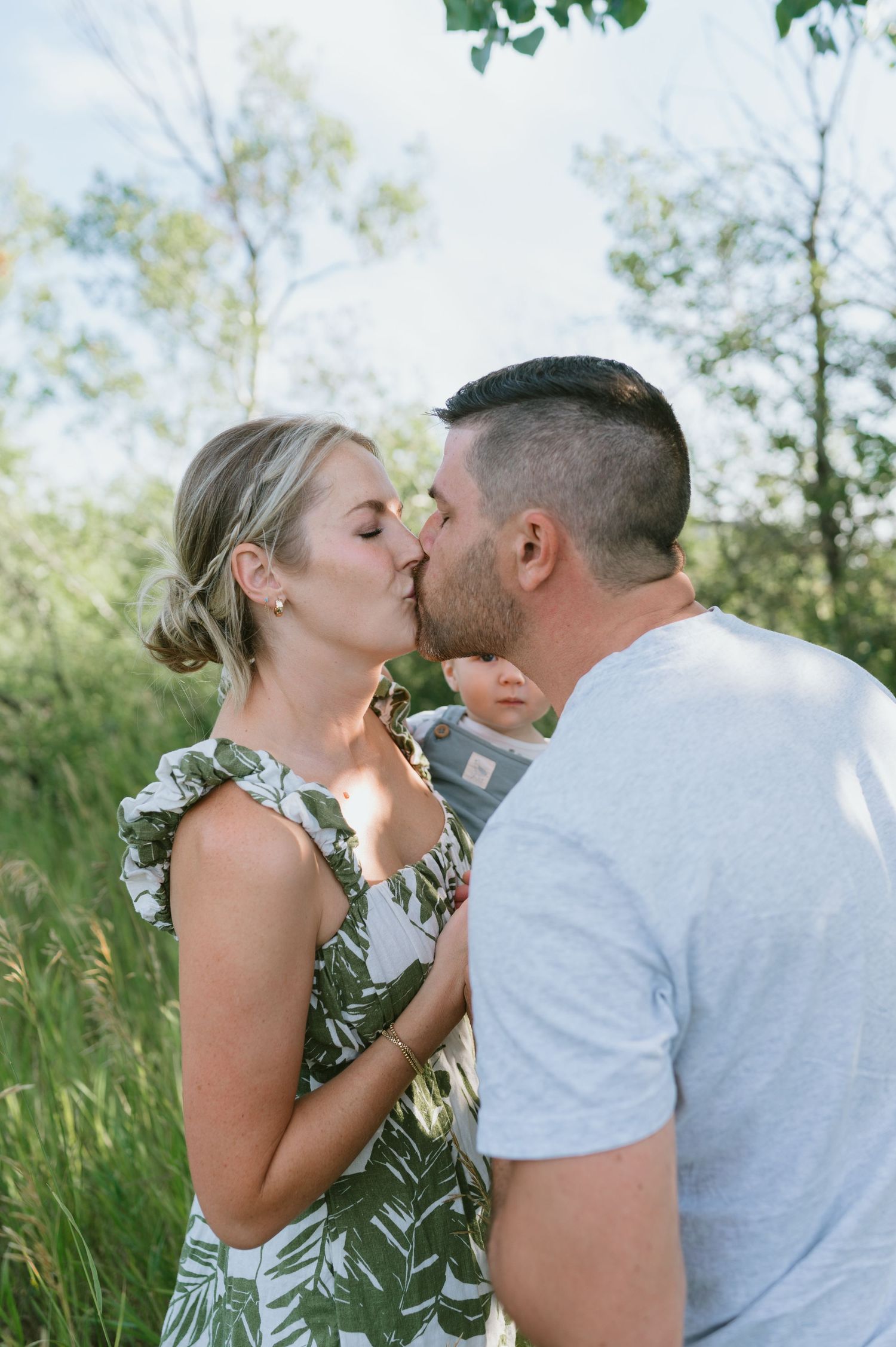 Couple sharing a romantic kiss in a lush summer garden setting.