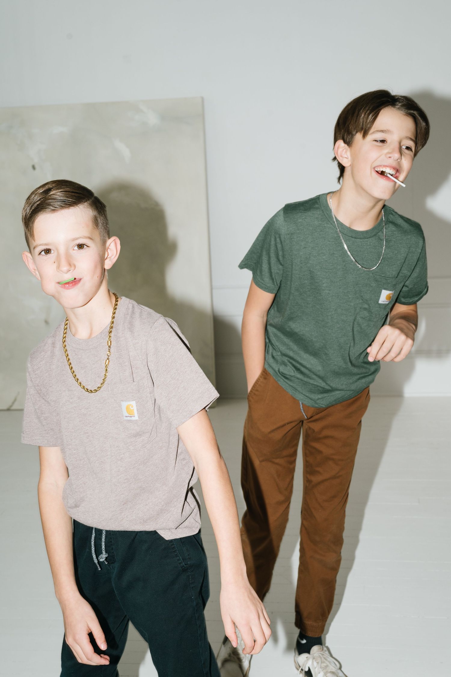 Two young people in casual t-shirts and pants posing playfully against a light background.