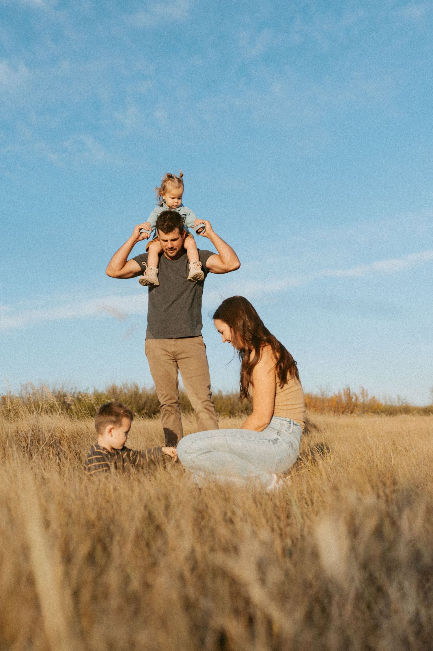 Family spending time together in a golden wheat field during sunset.