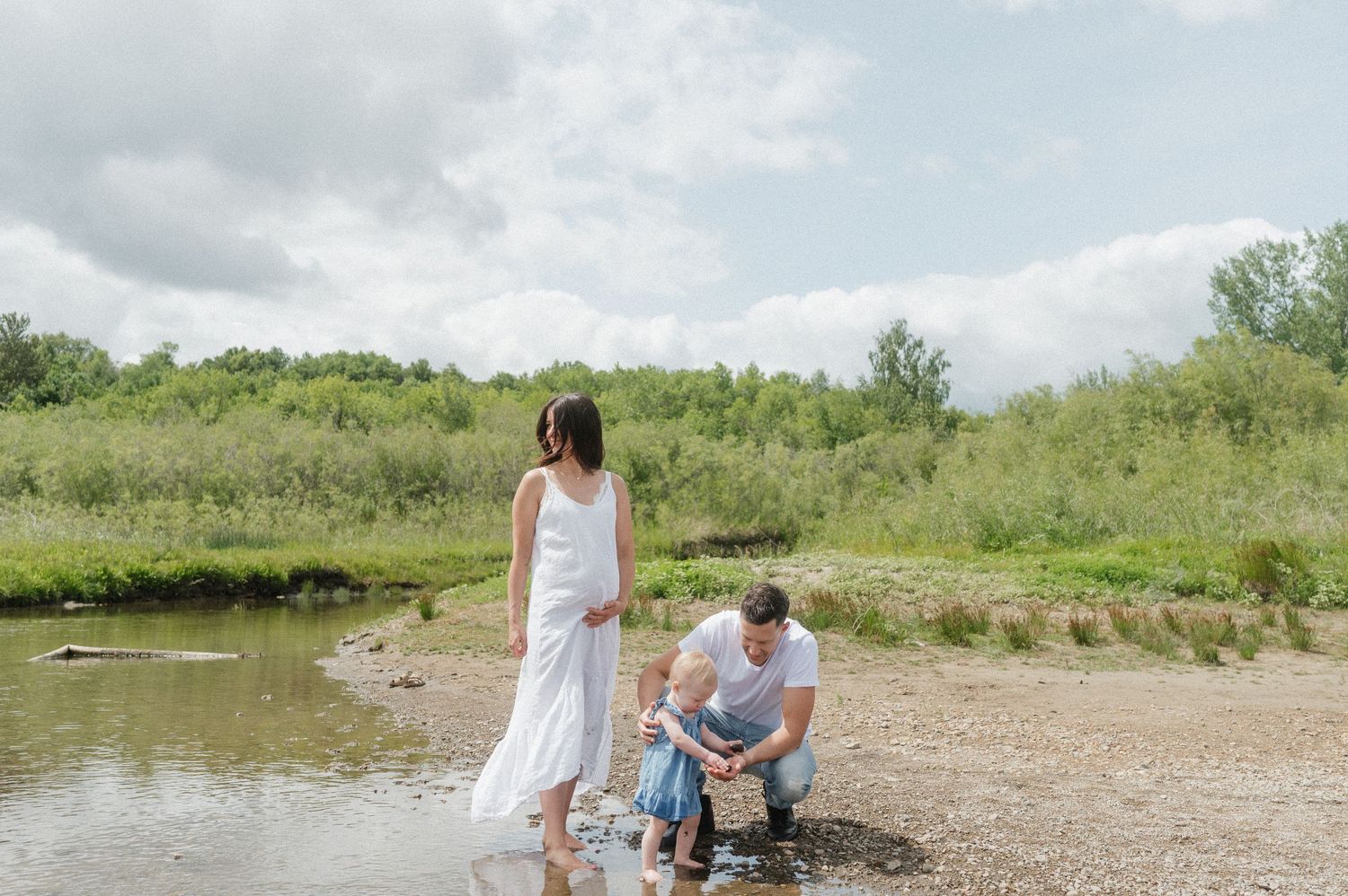 Family spending time together near water's edge on summer day.
