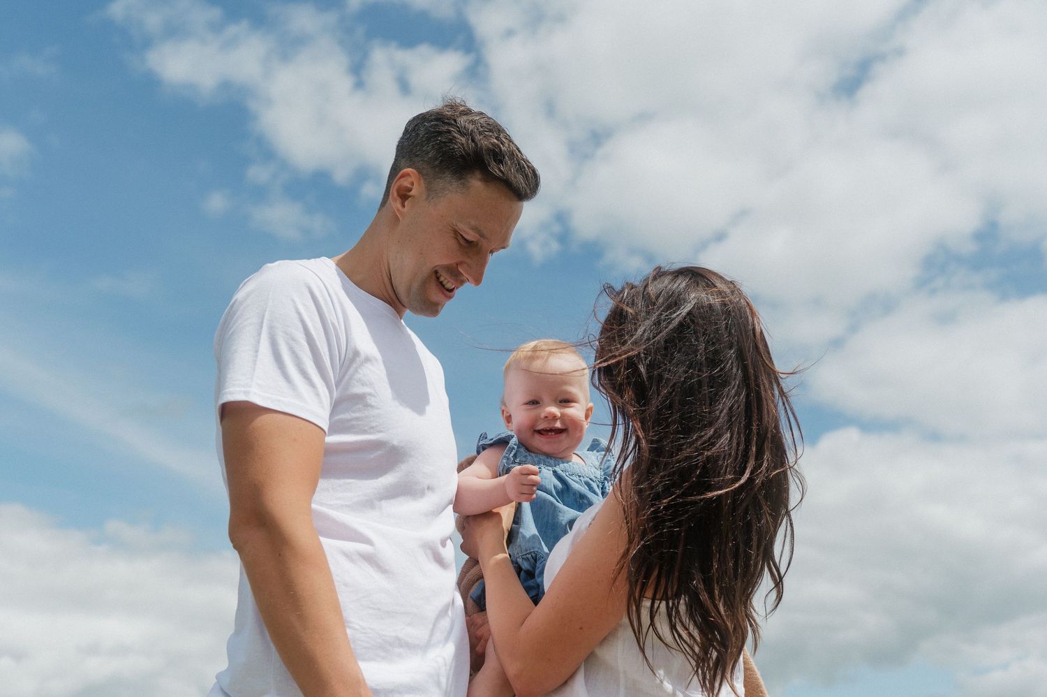 Family sharing joyful moment together against blue summer sky.