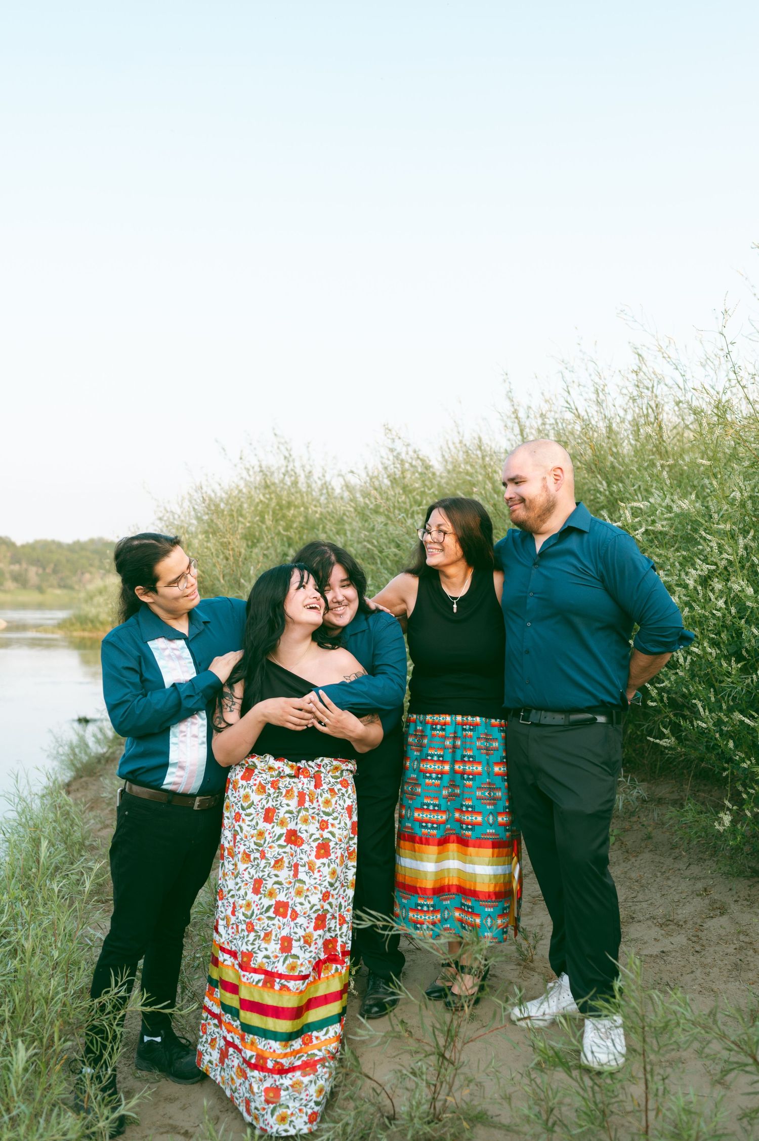 A group wearing colorful outfits poses together by a waterfront path.