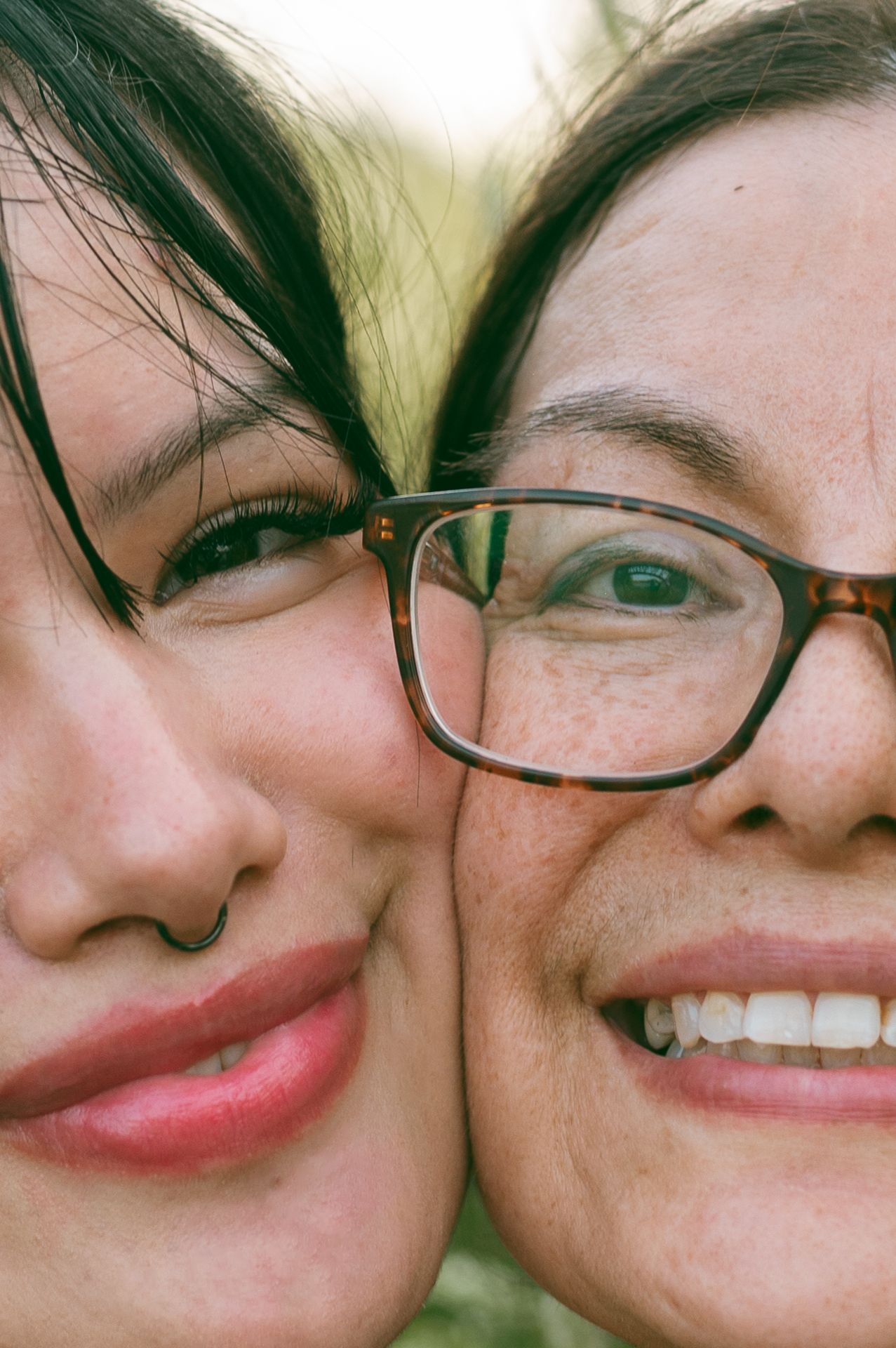 Close-up portrait of two smiling women with one wearing glasses.