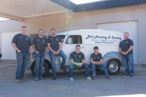 Group of workers lined up against a white building exterior.