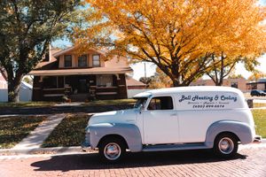 Vintage white cars parked under autumn trees with golden foliage.