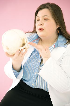Person in blue striped shirt and white lab coat poses with medical model.