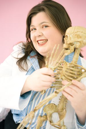 Person examining anatomical skeleton model while wearing professional attire.