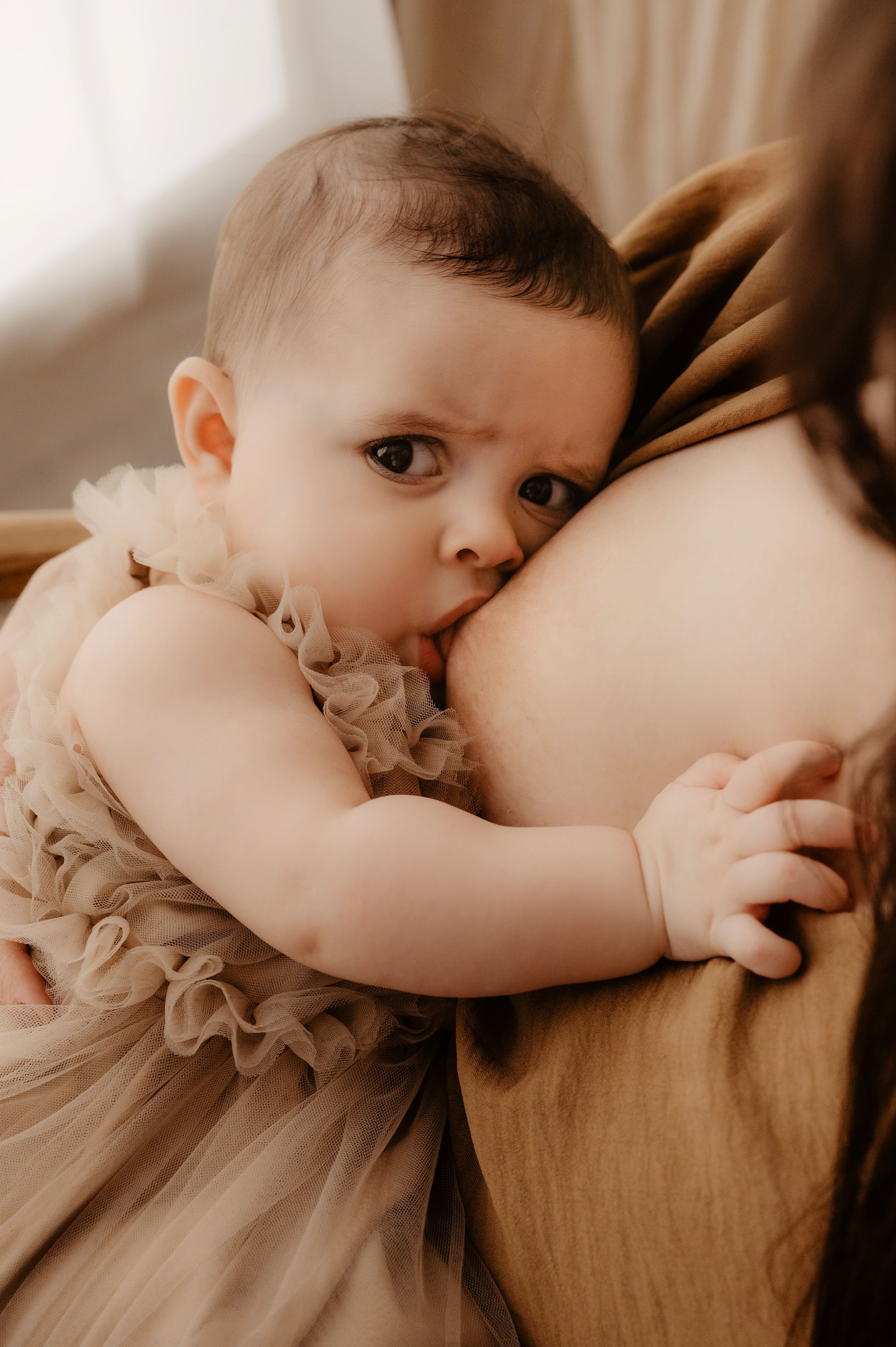 Close-up shots of mother and baby sharing tender moments in soft peach-colored outfits.
