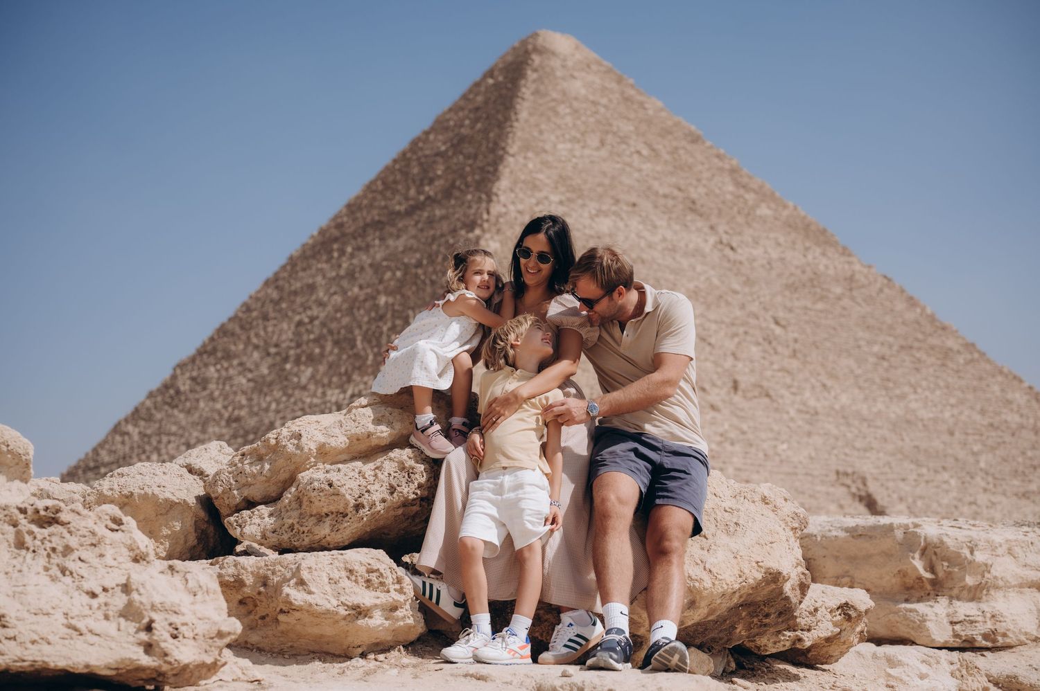 Group poses together on rocky terrain with Great Pyramid of Giza in background.