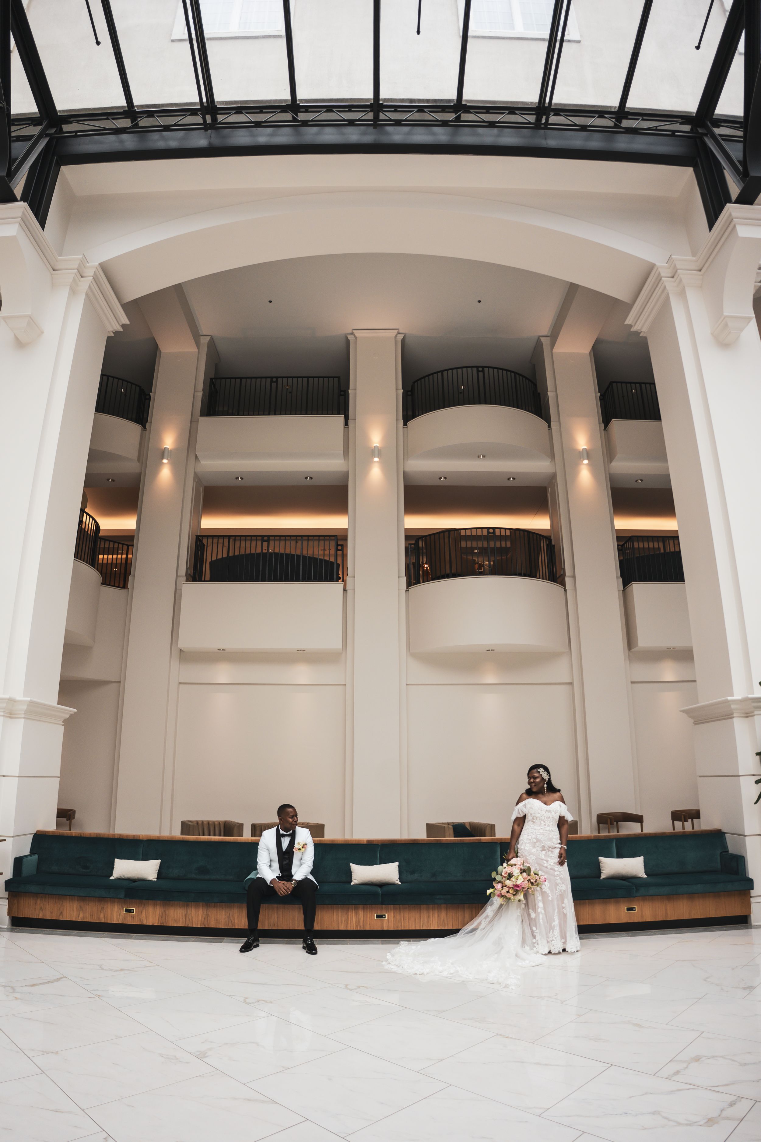 Wide panoramic view of a large modern wedding venue interior with white pillars and elegant teal decor details.