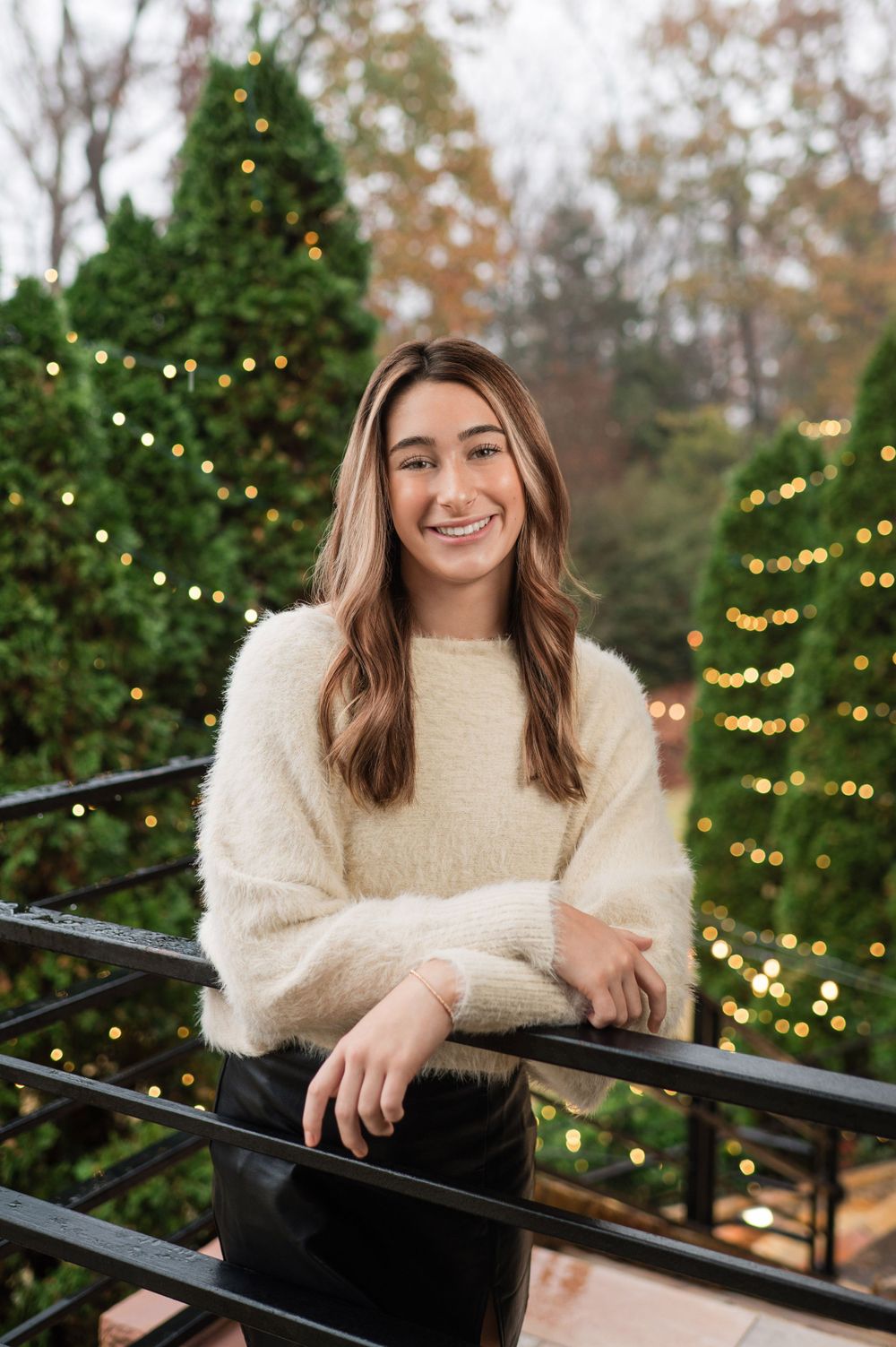 Teen girl portrait during the holidays with twinkling lights behind her.