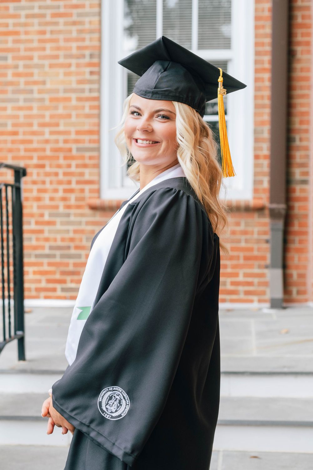 College graduate portrait in her cap and gown at the college campus.