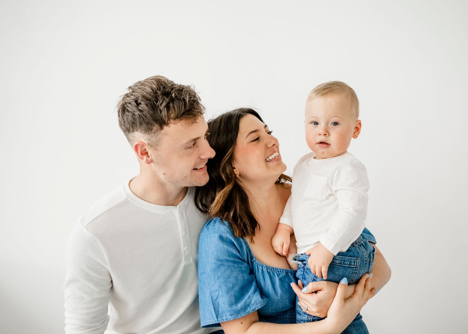 Family shares joyful moment together in bright white studio setting.