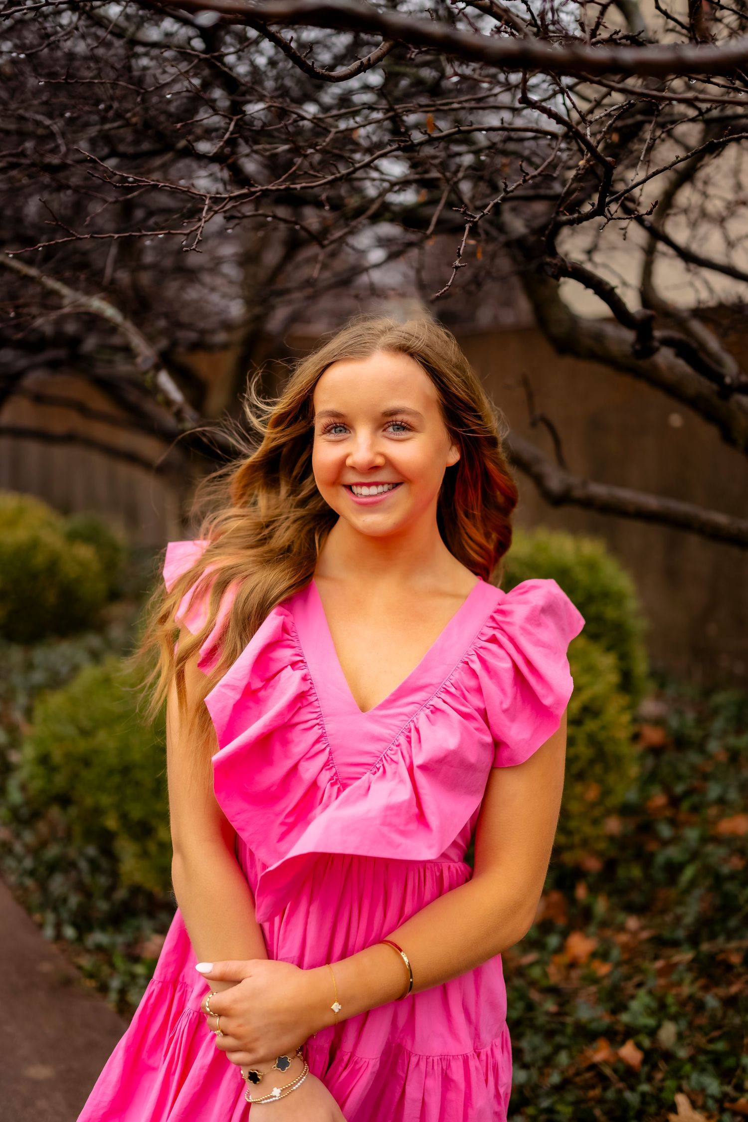 A bright pink ruffle dress photographed in a garden setting during autumn.