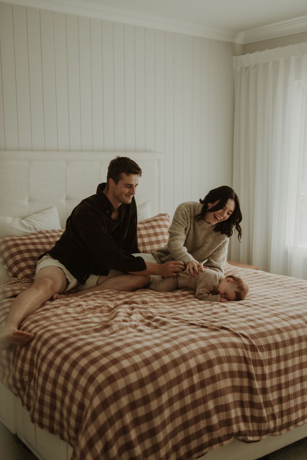 Intimate scene on a gingham-covered bed with people relaxing together in casual attire.