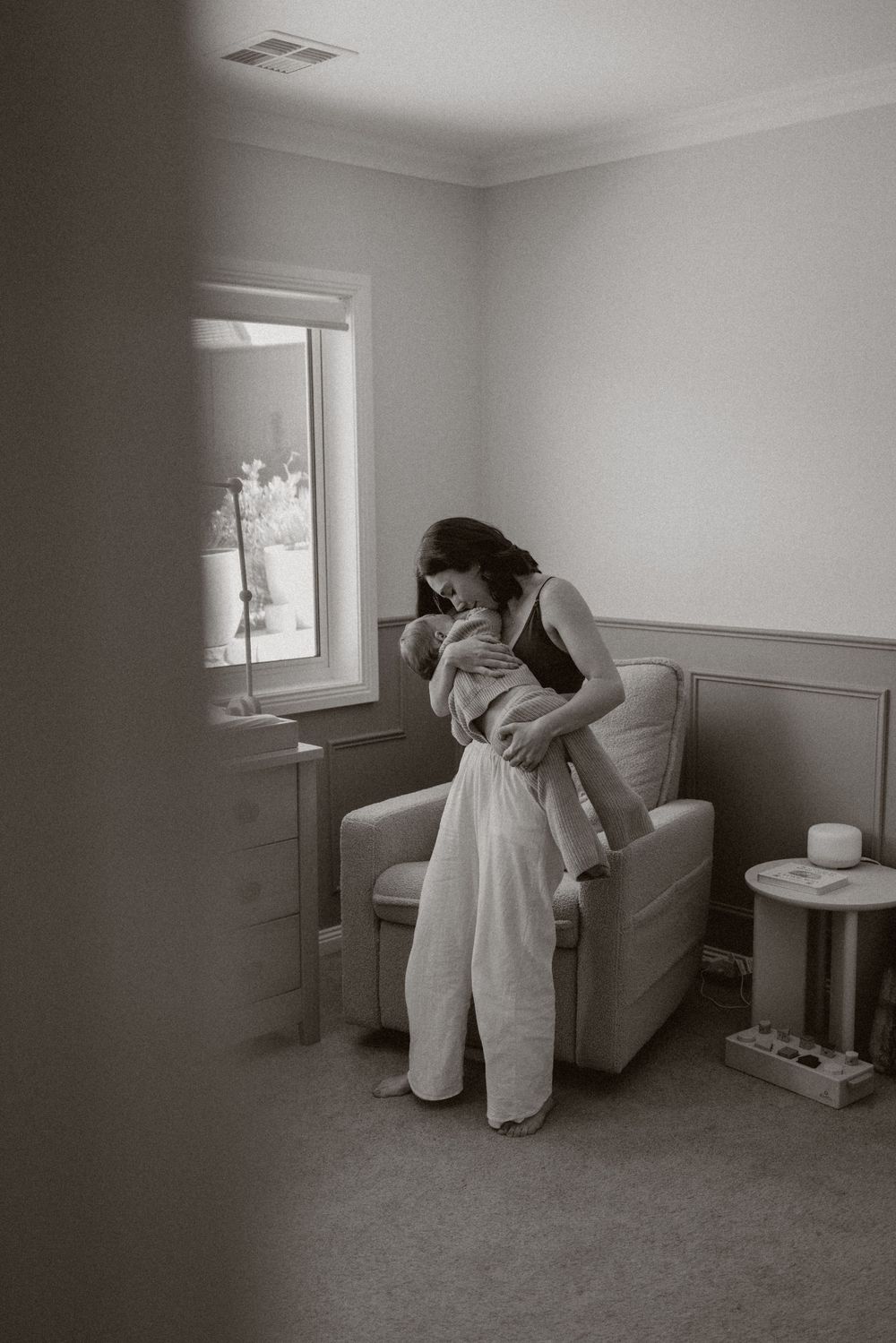 A series of black and white photographs showing a figure in white clothing interacting with furniture in a minimalist room.