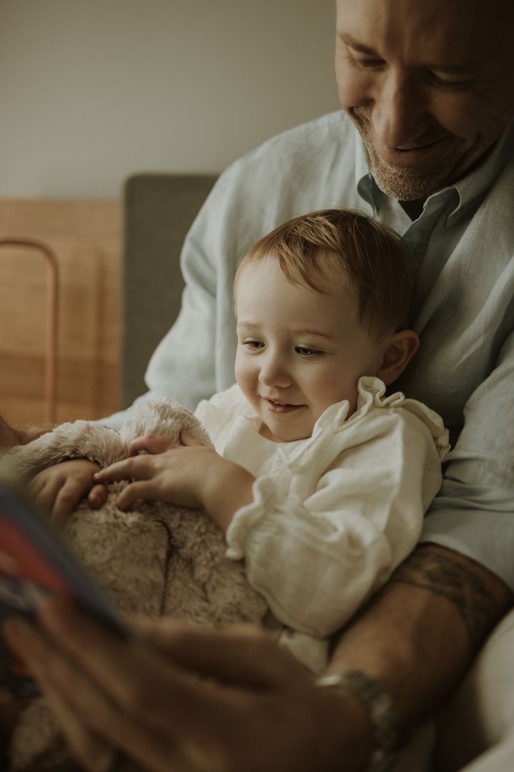 A tender reading moment captured between parent and child with a cozy sweater and book.