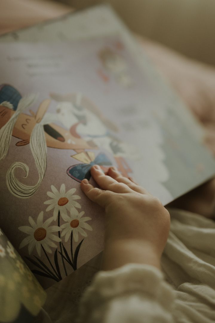 Close-up view of hands touching an illustrated book with floral designs and daisies.