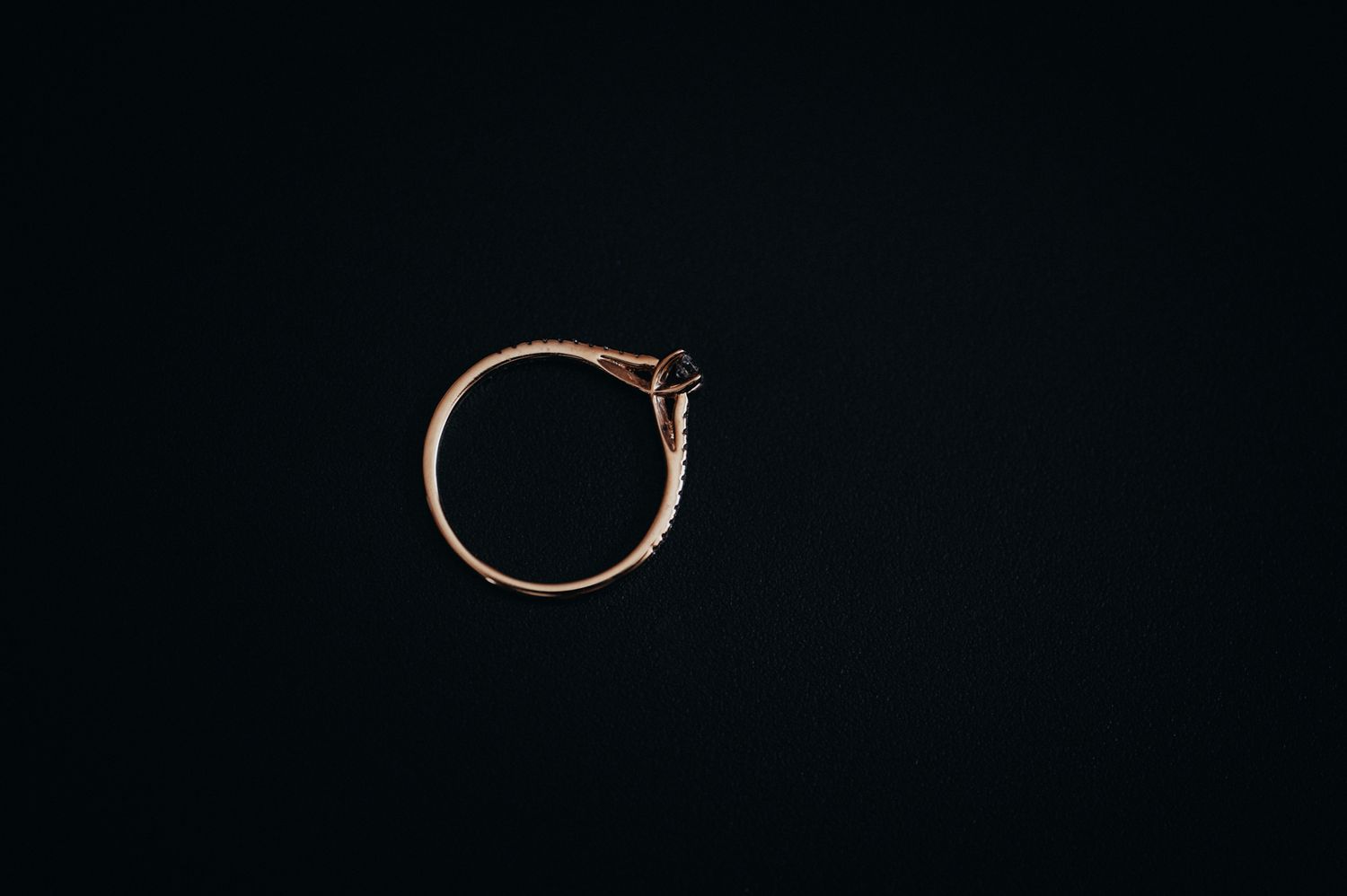 Delicate engagement ring photographed against black background.