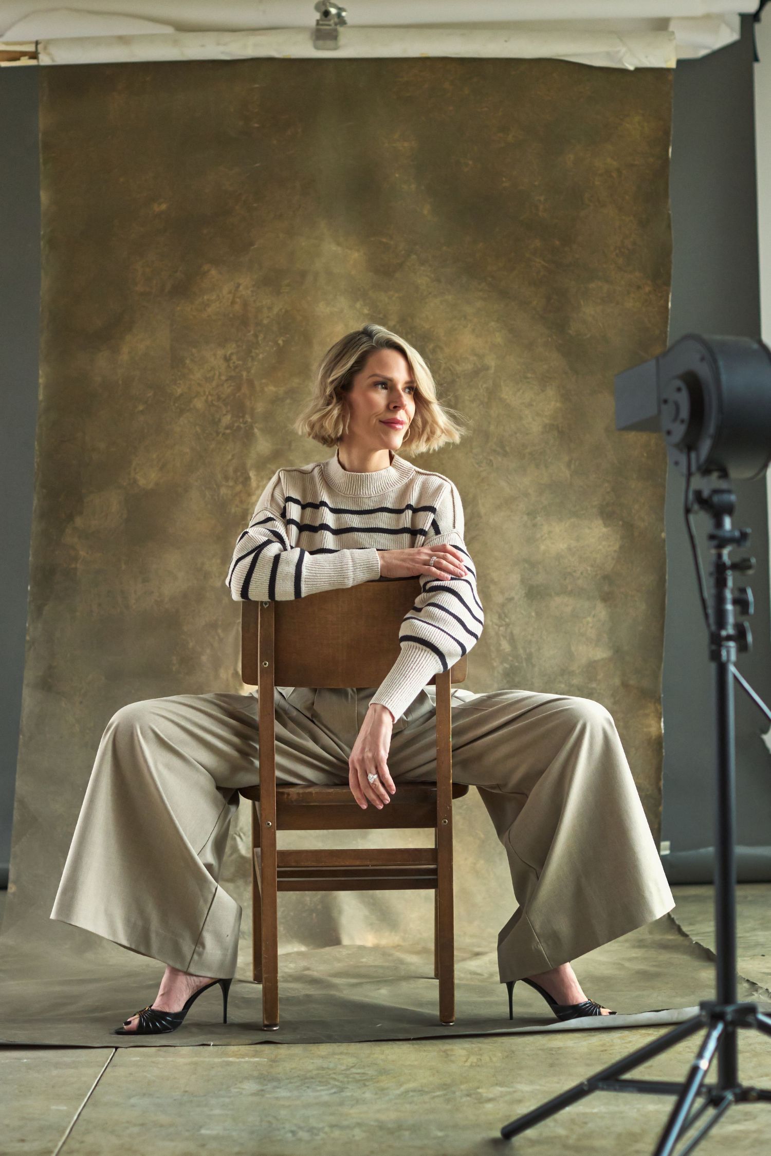 Studio photoshoot setup with wooden chair against textured backdrop.