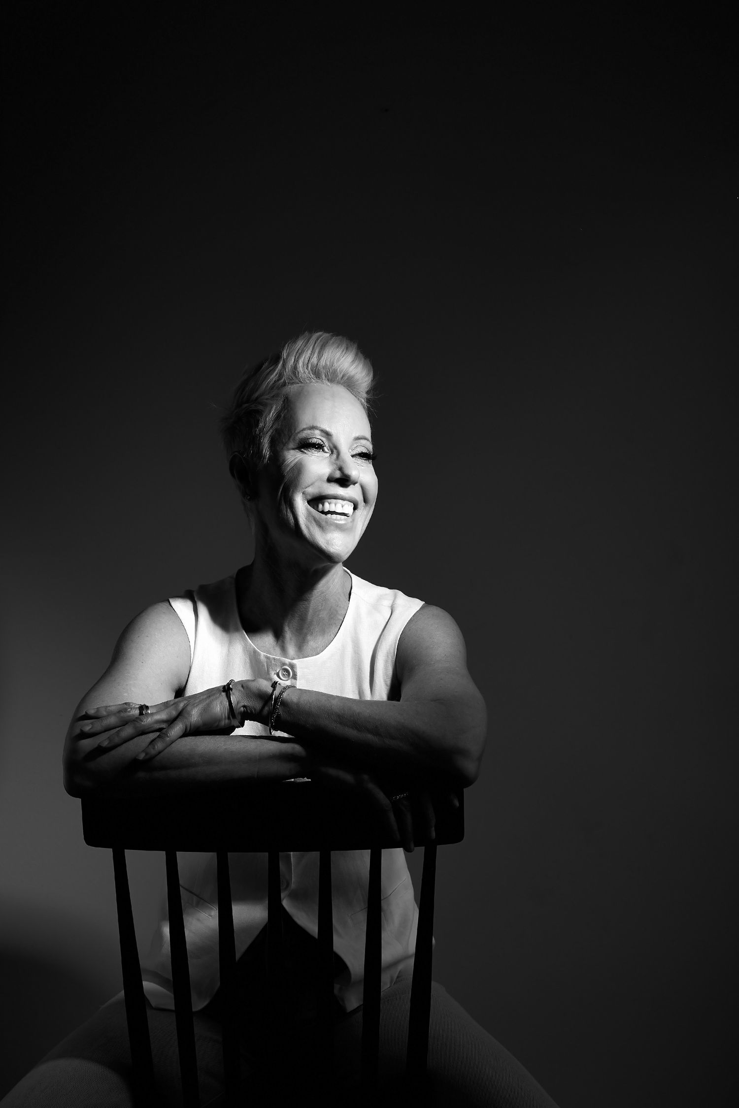 Black and white portrait series showing joyful expressions while leaning on chair.