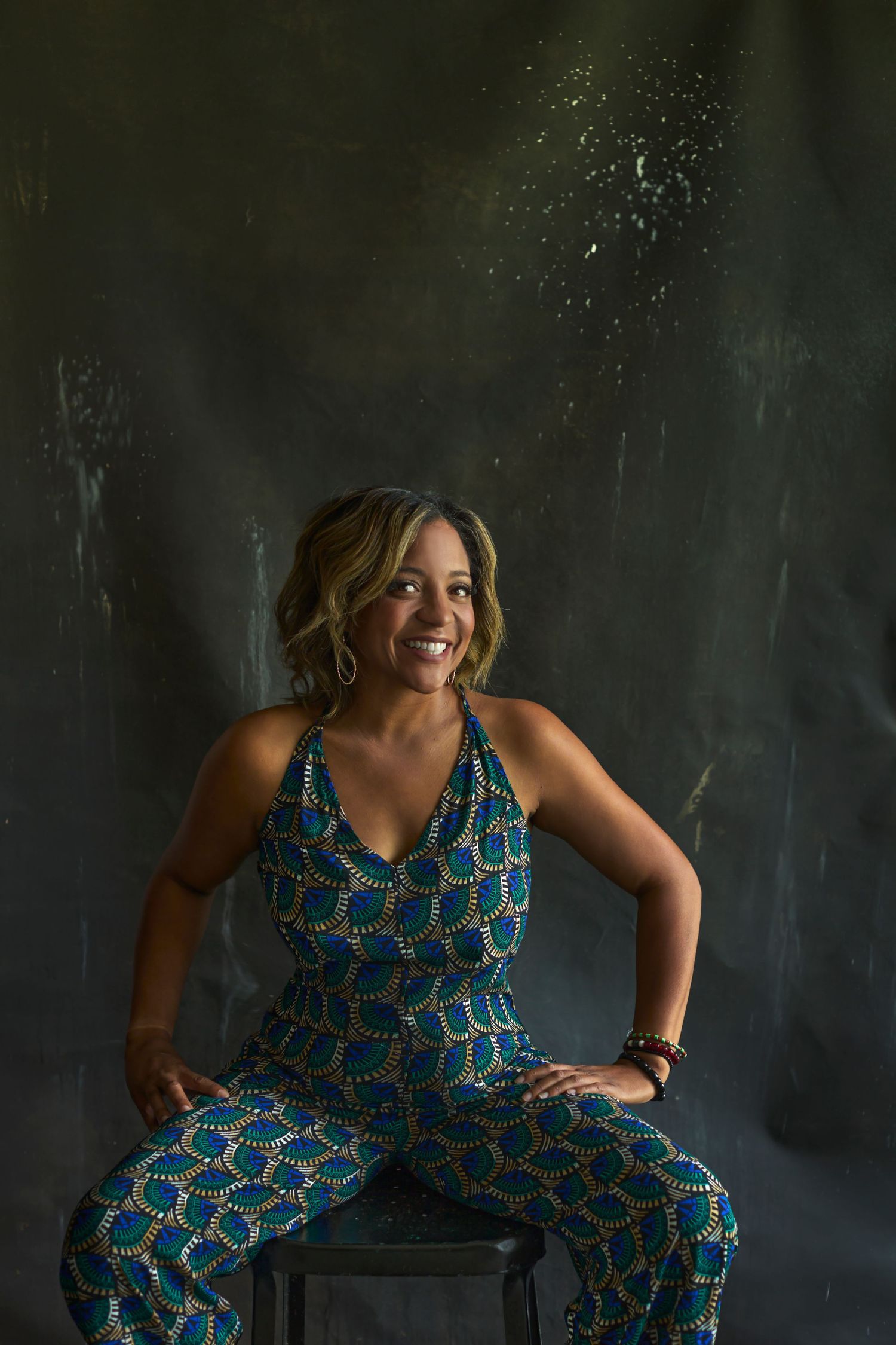 Dynamic studio portrait with colorful patterned outfit against dark background.