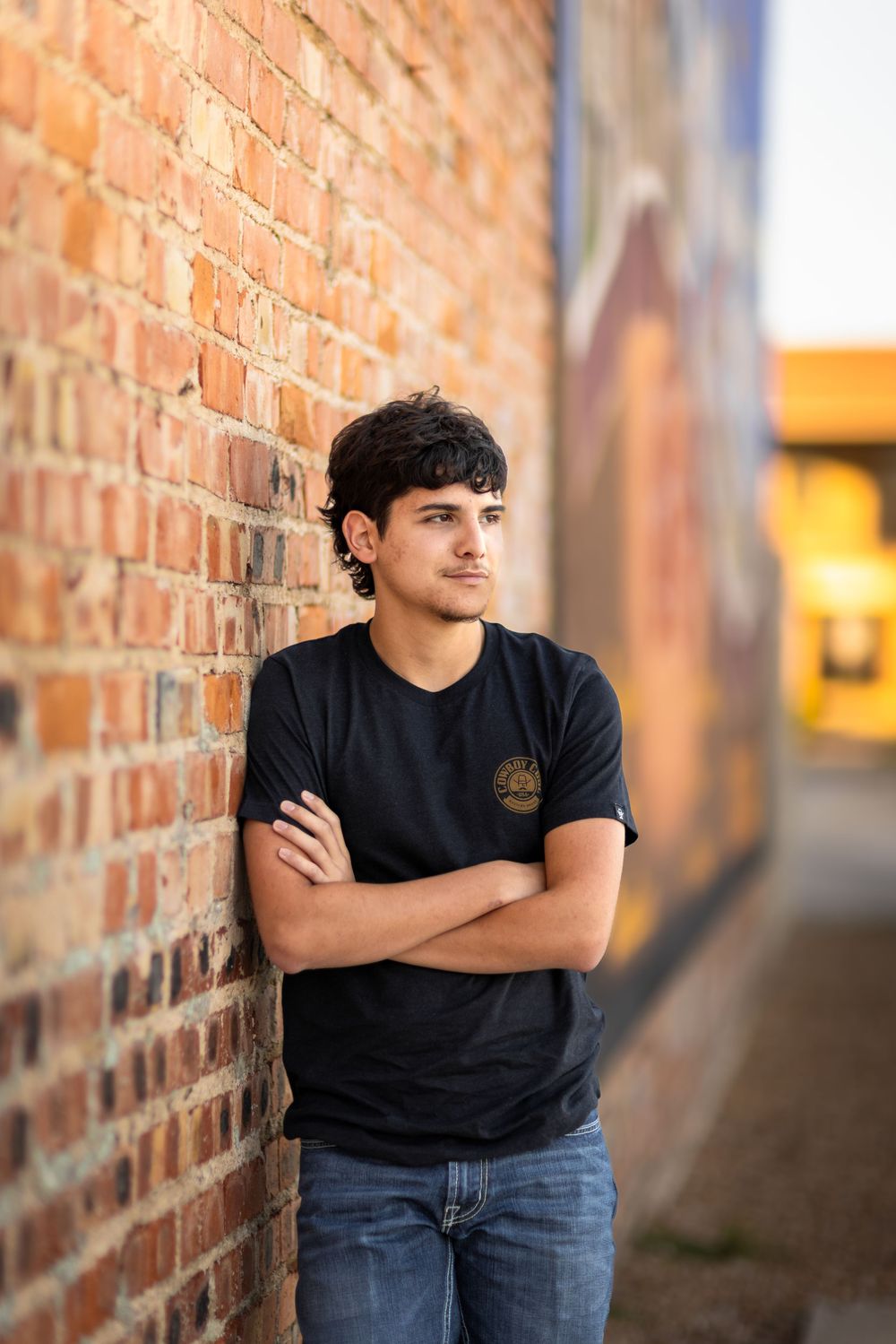 Person in black shirt leaning against rustic brick wall.