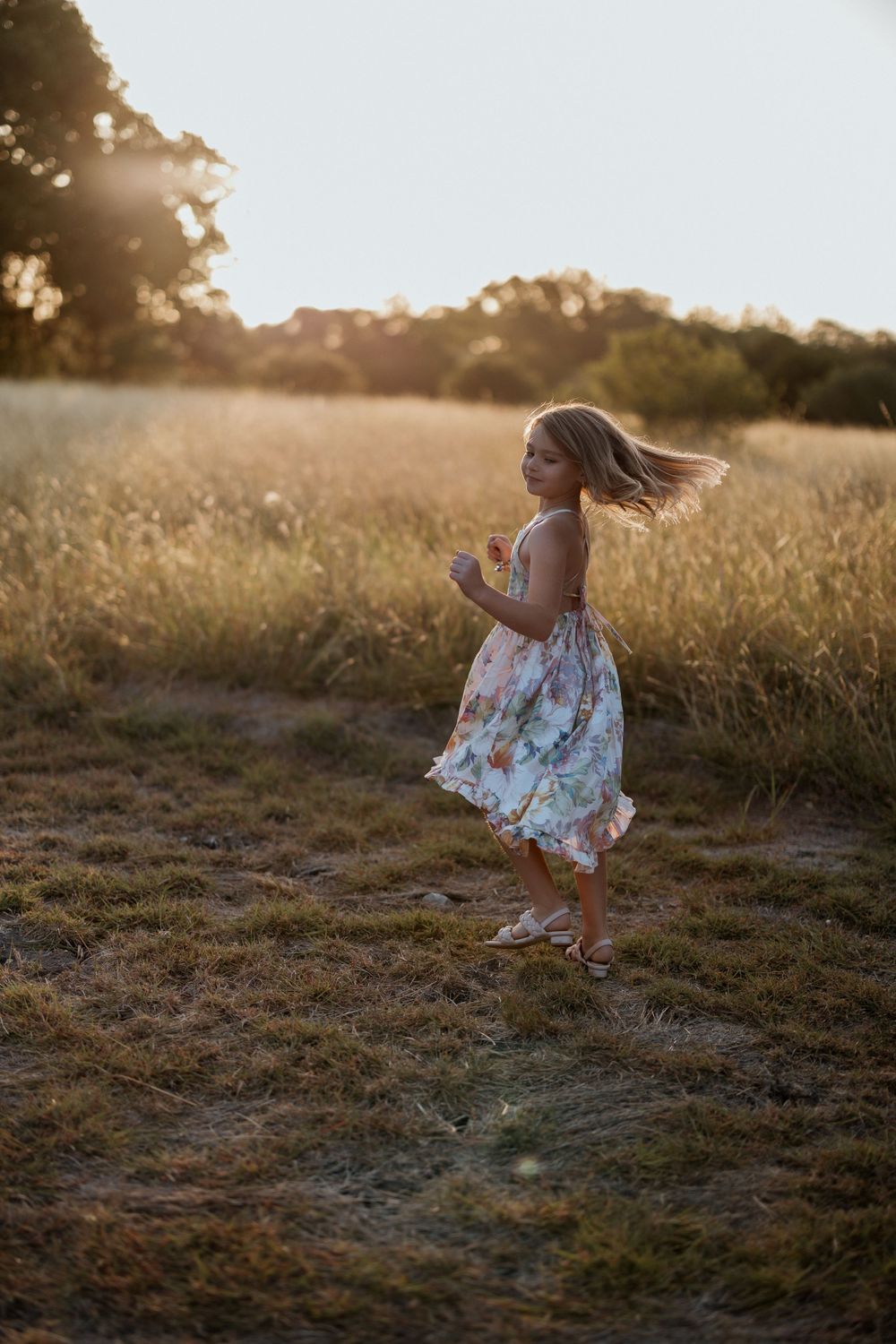 A floral sundress twirls in the golden light of sunset as someone dances joyfully through a wildflower meadow.