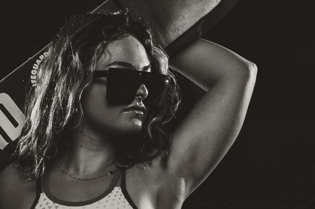 Artistic black and white portrait with sunglasses and moody lighting.