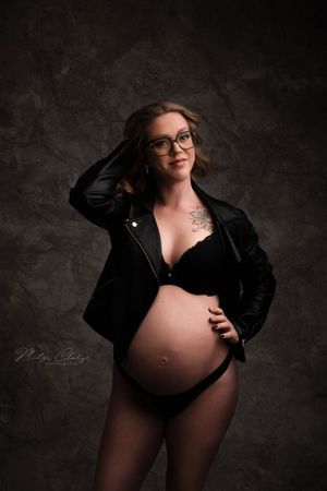 Zwangere vrouw met zwart jasje tijdens zwangerschaps fotoshoot