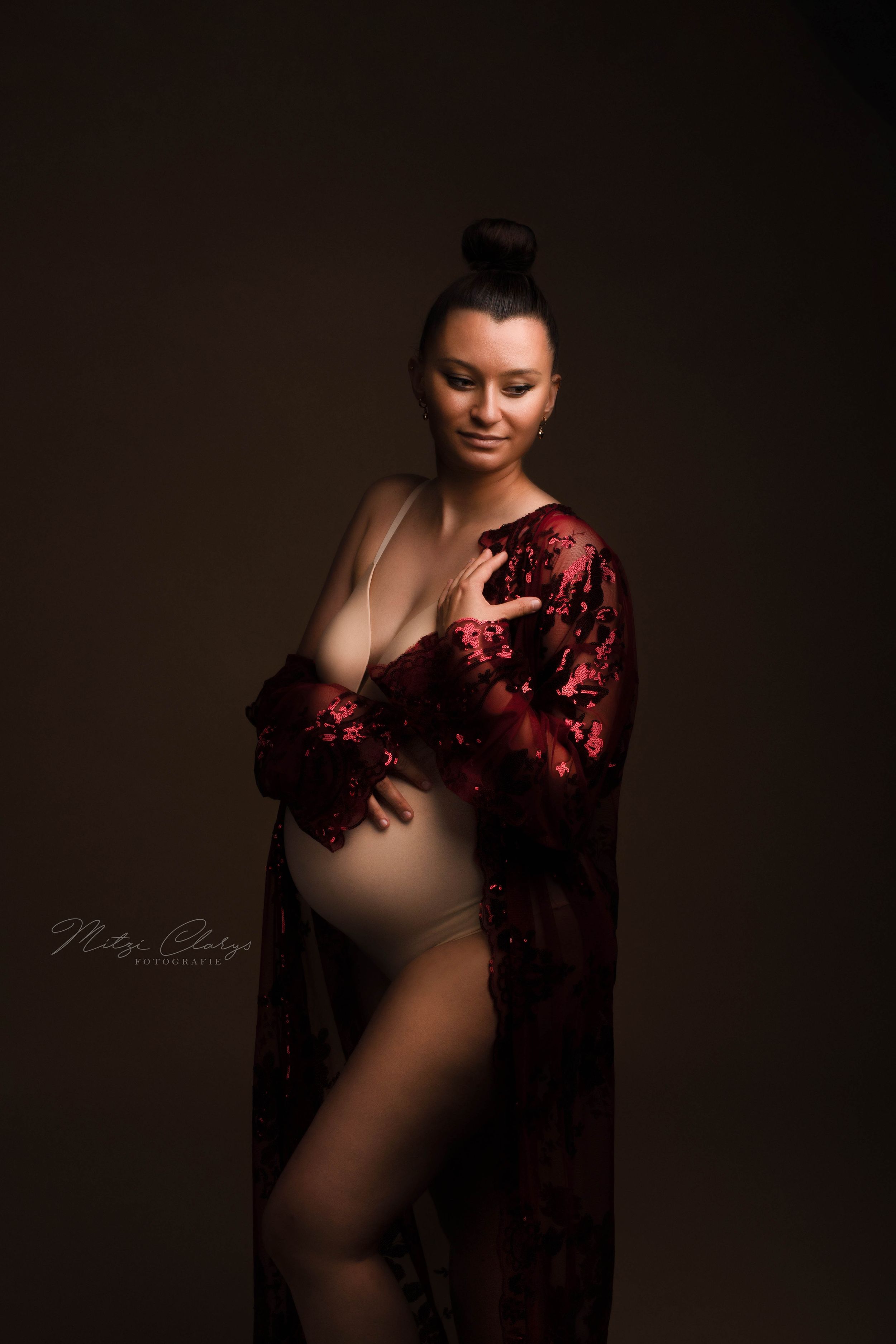 Portret van zwangere vrouw in rode kimono tijdens zwangerschaps fotoshoot