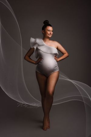 Portret van zwangere vrouw in witte minimalistische body tijdens zwangerschapsshoot in studio Goes