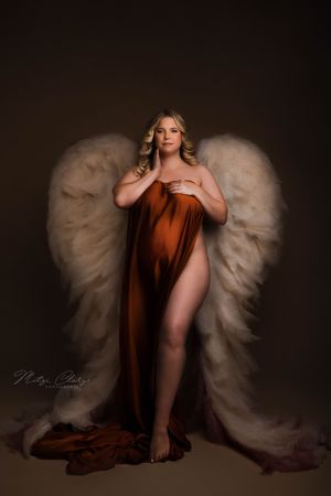 Zwangere vrouw poseert met engelenvleugels tijdens zwangerschaps fotoshoot in Goes