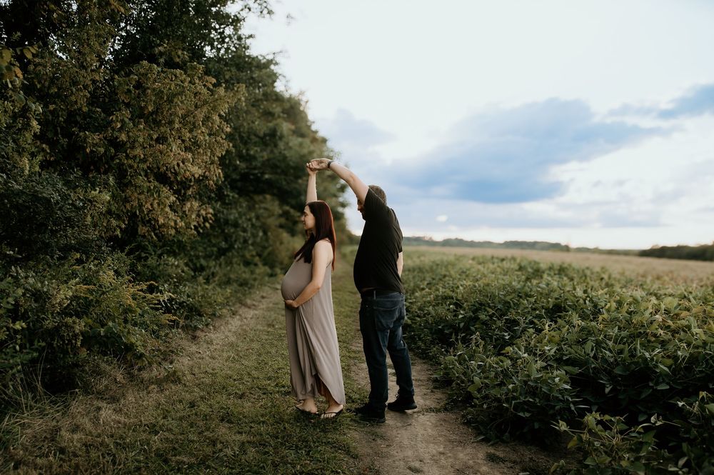 Romantic outdoor photoshoot in a lush agricultural field on a cloudy day.
