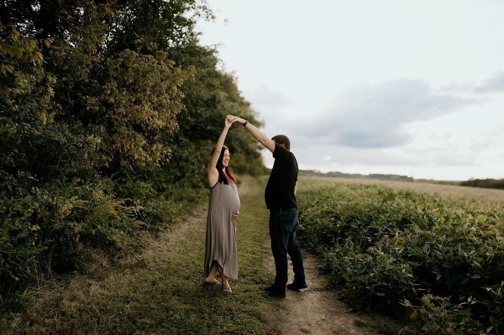Loving couple poses together on a rustic dirt path through farmland.