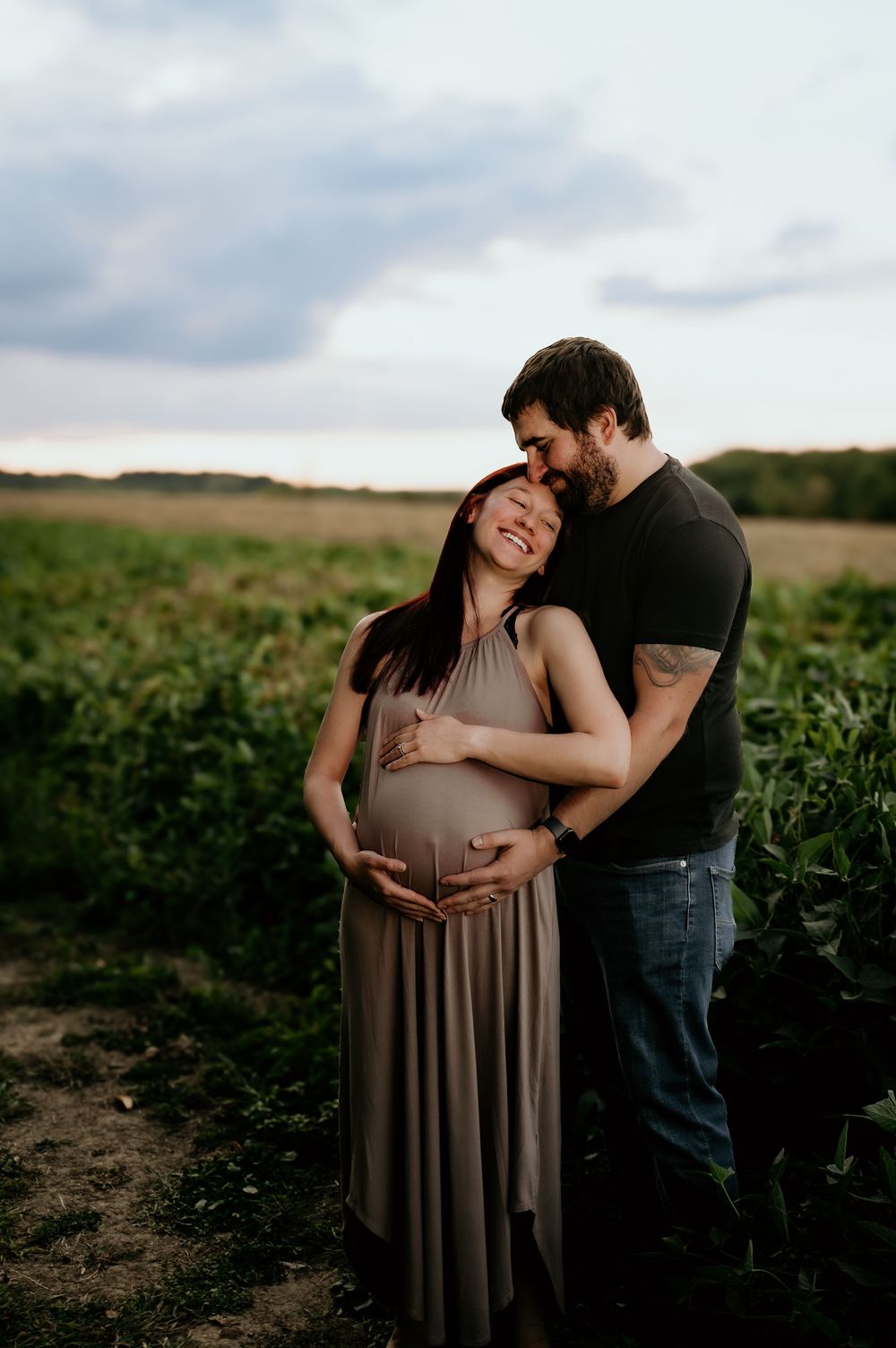 Expecting couple shares joyful moments together in a farm field.