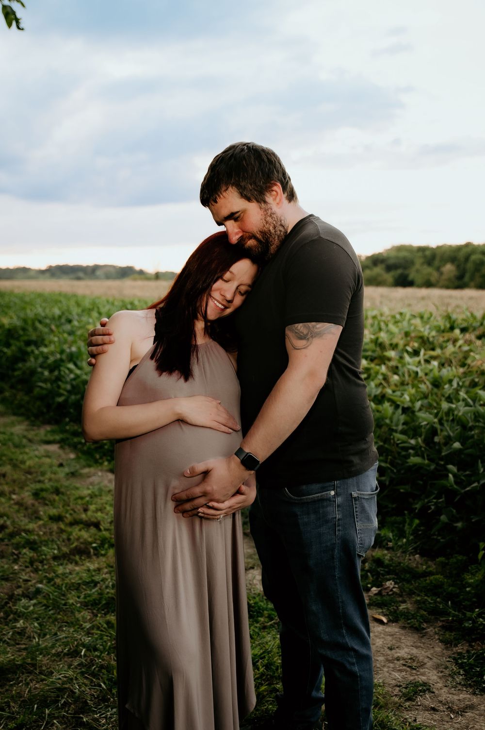 Loving maternity moment captured between couple in farm field.