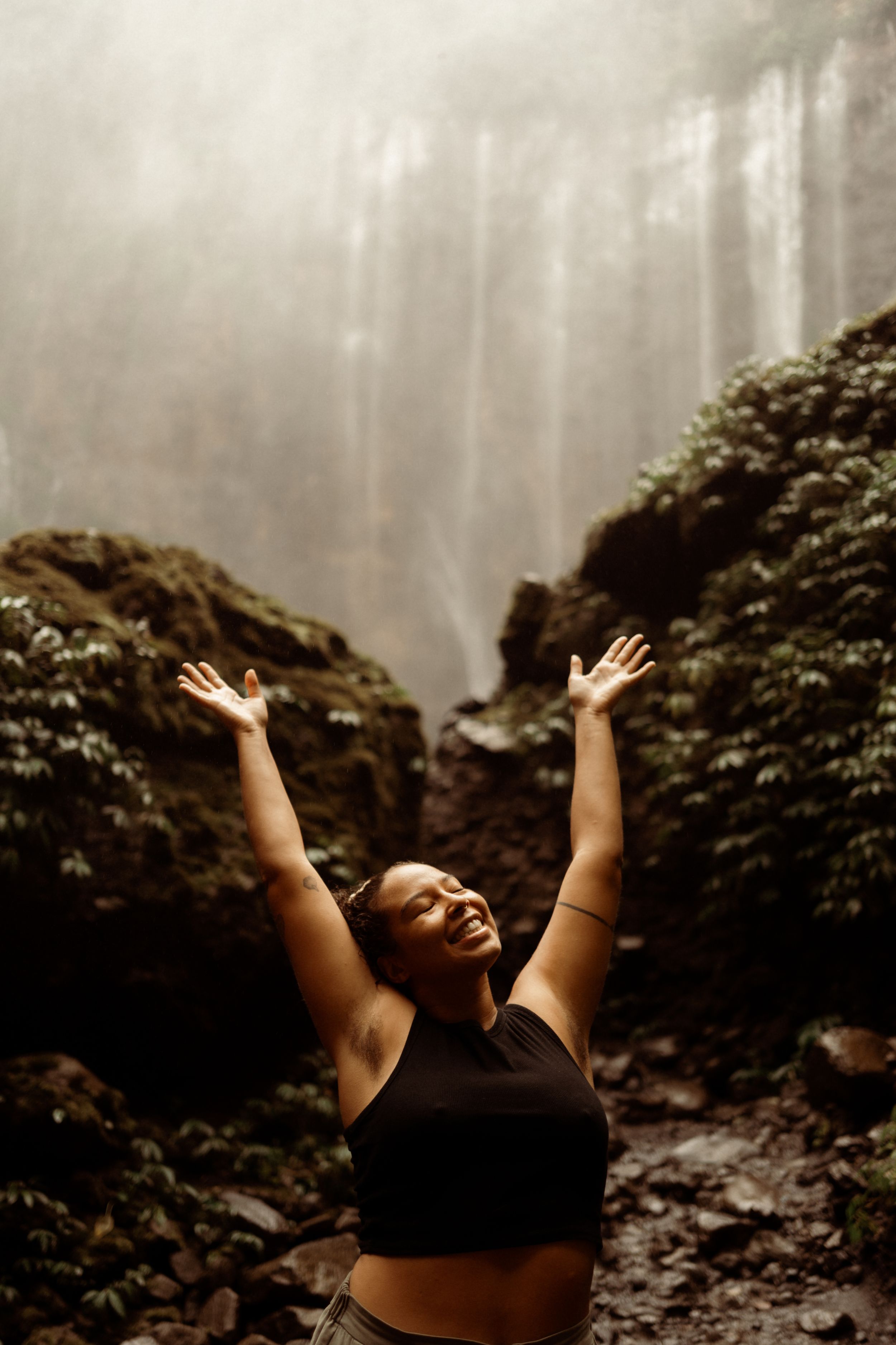 A candid portrait showing natural laughter and joy with dreadlocks in warm lighting.