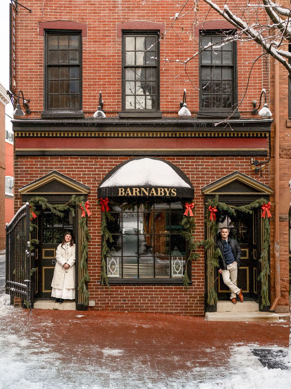A historic red brick storefront with 'Barnabys' signage and snow-covered entrance during winter.